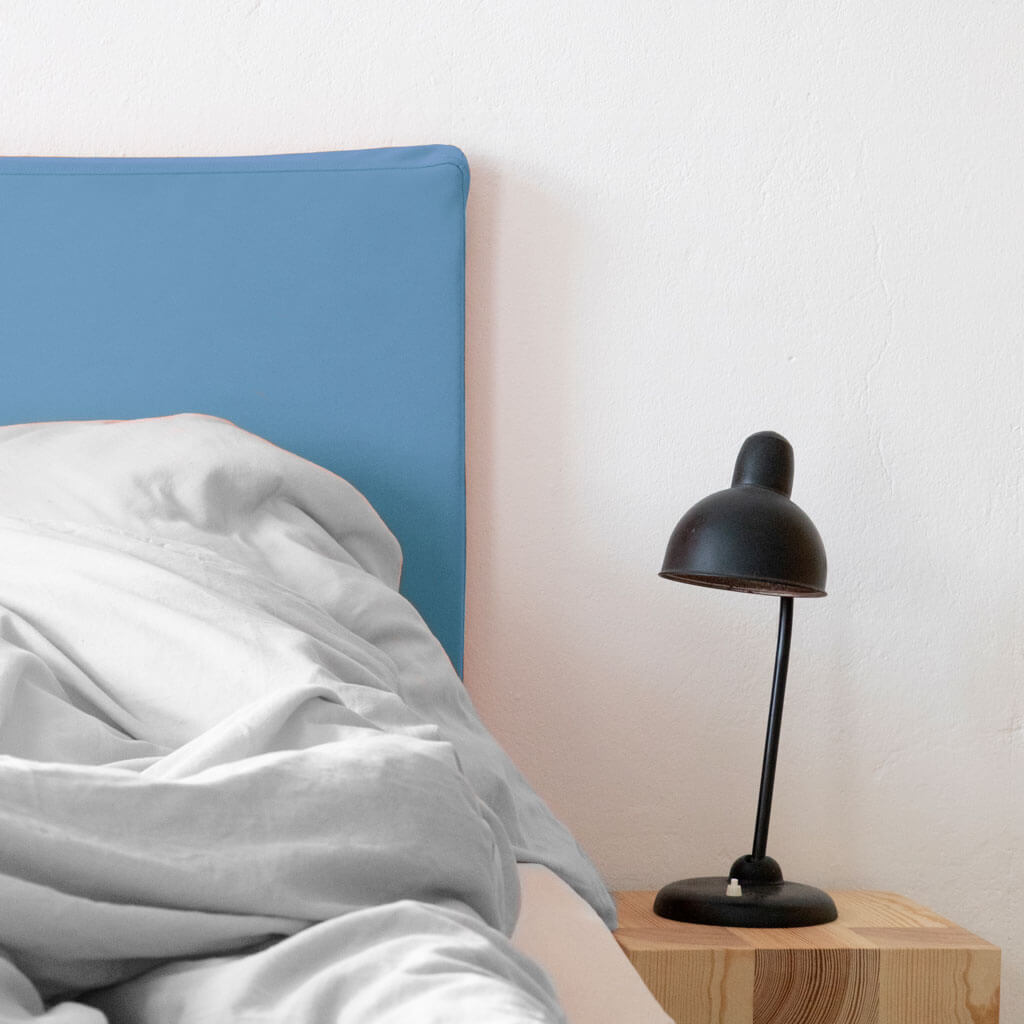 Bettkopfteil in kornblumenblau mit grauer Bettwäsche